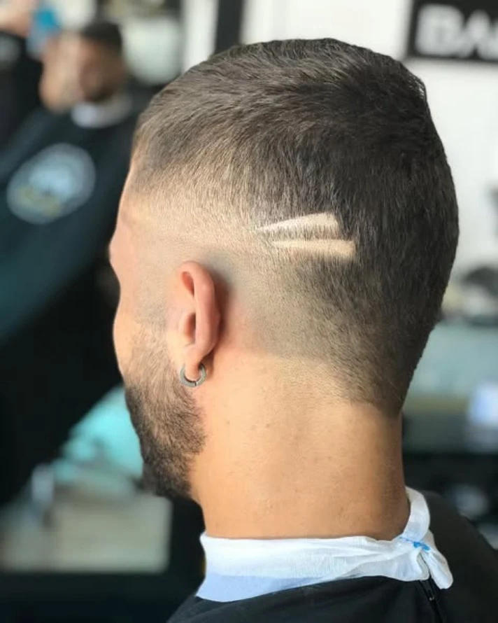 Nuca de um cliente com fade e risco marcado na lateral.